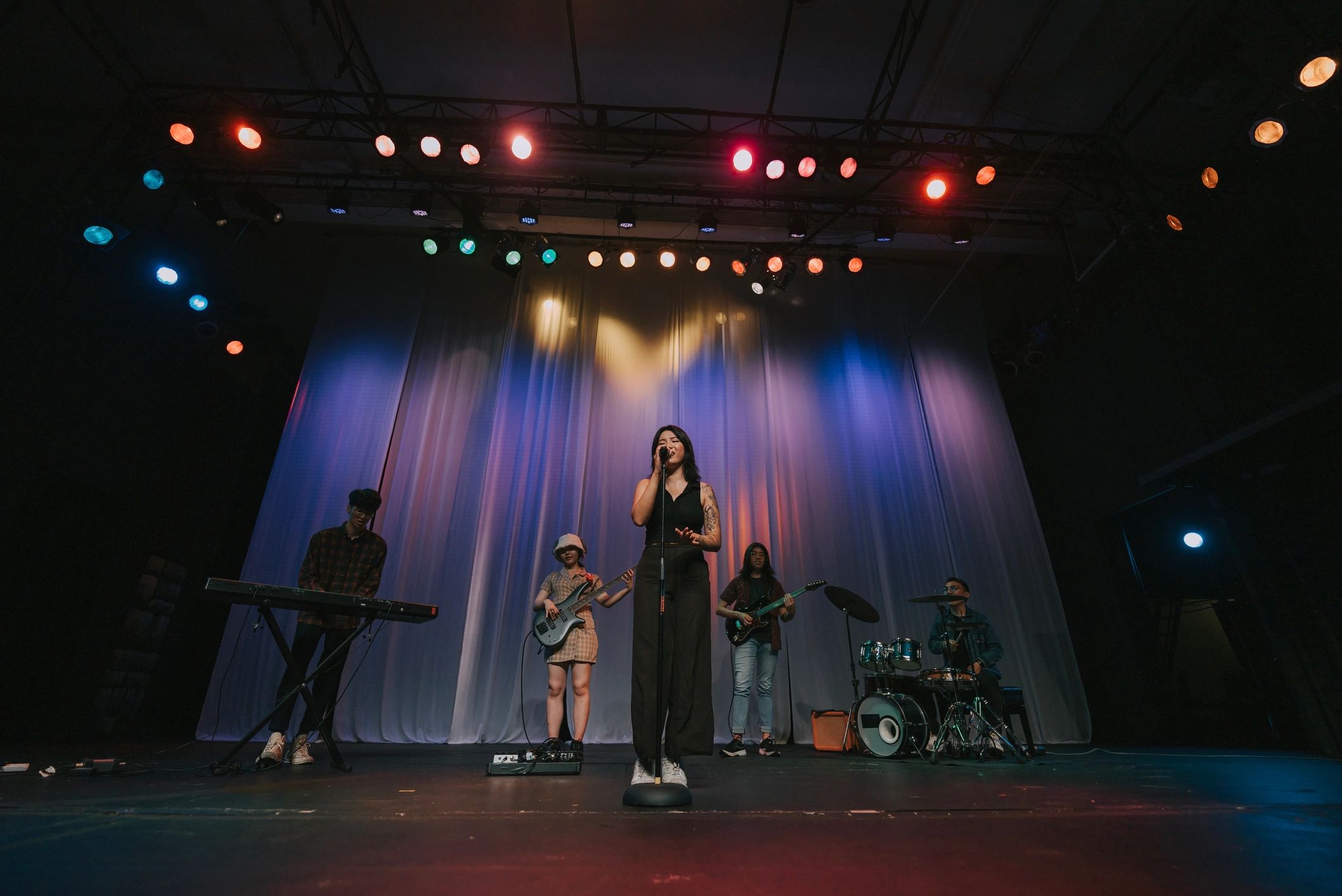 Lead singer and band performing under stage lights